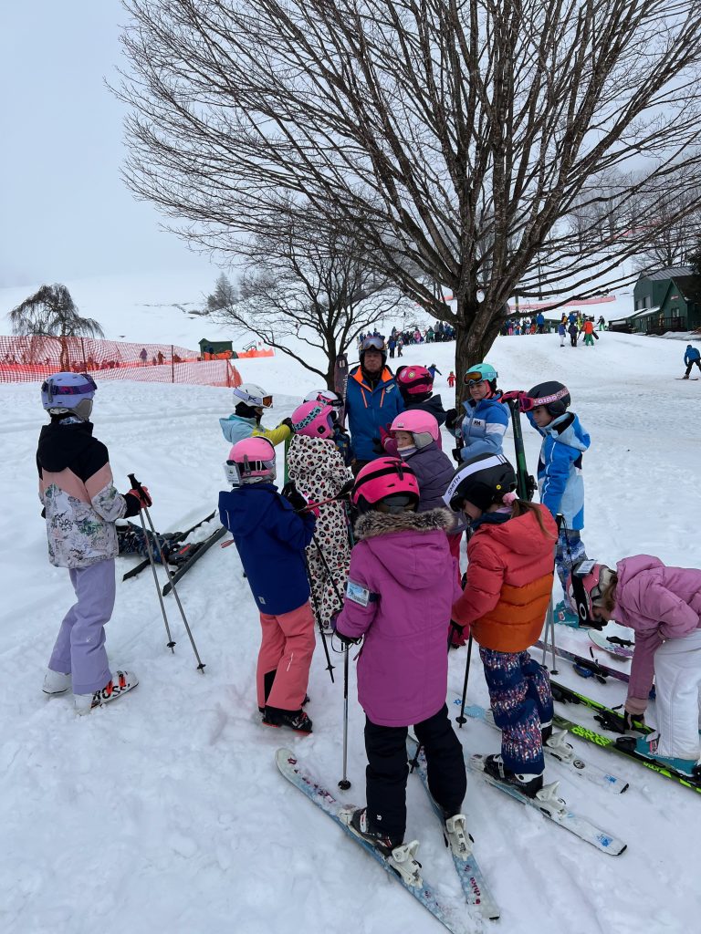 A ski instructor talking in a group with a group of young female skiiers.