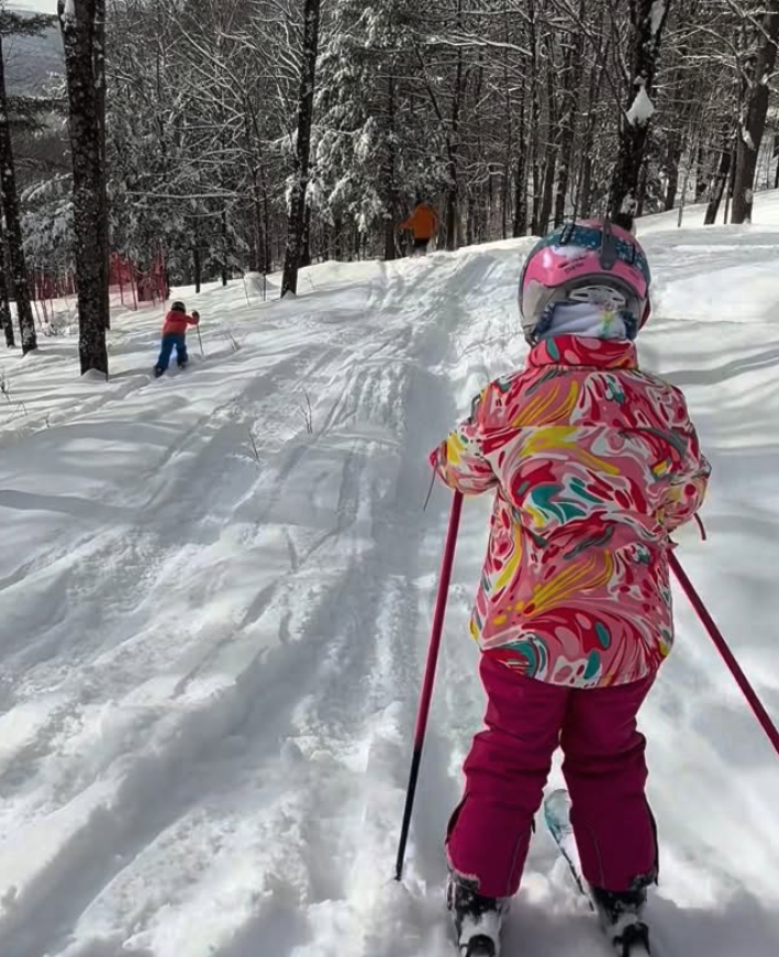 Photo of a girl skiier in a bright and colorful jacket.