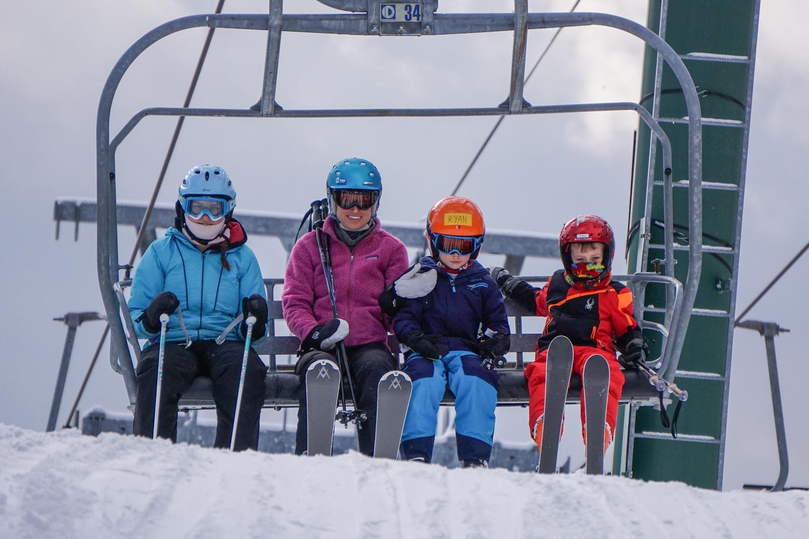 Four people on a ski lift at the Quechee Club